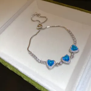 Vue détaillée d'un bracelet argenté avec trois zircons bleus étincelants en cœur.