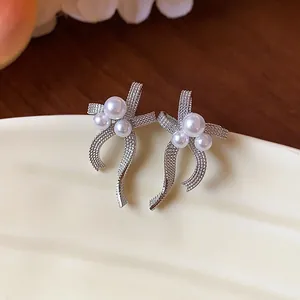 Close-up view of elegant silver bow earrings featuring lustrous white pearls