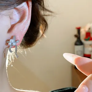 Close-up of elegant silver bow earrings with three white pearls on a woman ear