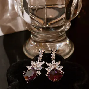 Close-up of elegant banquet earrings with purple stones and marquise-cut zircons.