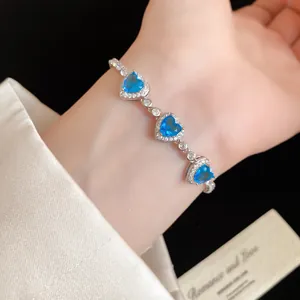 Vue détaillée d'un élégant bracelet cœur en zircon bleu porté au poignet avec soie