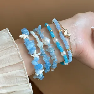 Vue détaillée des bracelets superposés en aigue-marine bleue avec un pendentif cœur doré