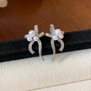 Detailed macro shot of elegant silver-tone bow earrings with pearl cluster accents