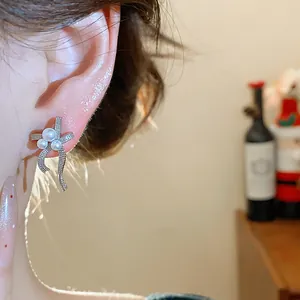 Close-up view of elegant French style bow-shaped pearl earrings on a model's ear