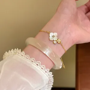 Detailed close-up of a elegant gold flower bracelet with white mother-of-pearl charms