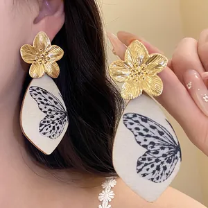 Close-up of vintage gold flower earrings with butterfly wing printed acetate drops