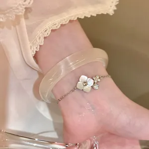 Detailed macro view of a silver flower bracelet with pearl petals and a cream bangle