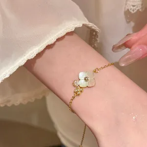 Close-up of gold floral bracelet featuring white shell flower and sparkling crystal charms