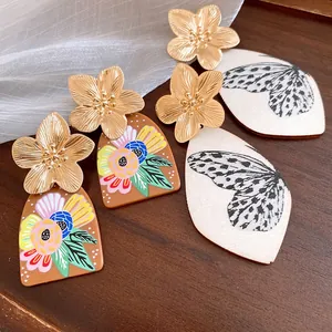 Close-up of floral and butterfly print acetate drop earrings with gold metal flowers