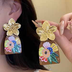 Macro view of vintage gold flower and colorful floral print acetate drop earrings
