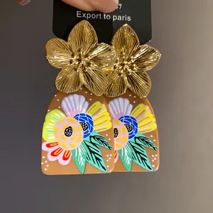 Macro view of metallic gold flower and colorful acetate floral print pendant earrings