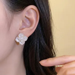 Elegantes pendientes de flor de perla con bordes perlados lucidos por una modelo de moda