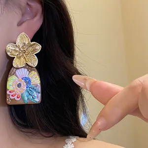 Close-up view of vintage gold metal flower earrings with colorful acetate floral print