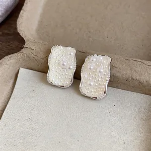 Detail of French minimalist square silver stud earrings with multi-size pearls