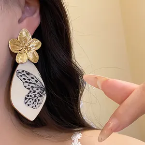 Detailed view of vintage gold flower earrings with butterfly wing printed pendant