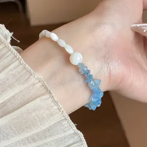 Vue macro détaillée d'un bracelet en aigue-marine et perles de nacre porté au poignet