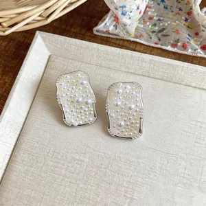 Close-up of elegant French-style square pearl stud earrings with silver details