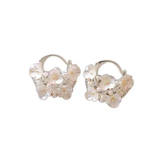 Elegant floral hoop earrings with pearls and rhinestones on a white background.