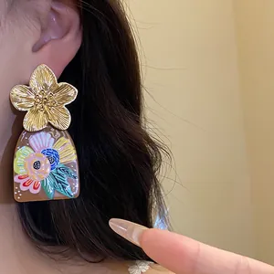 Detail view of ethnic style vintage earring with golden metal flower and printed acetate