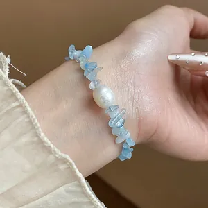 Gros plan d'un bracelet élégant en aigue-marine naturelle et perle sur un poignet.