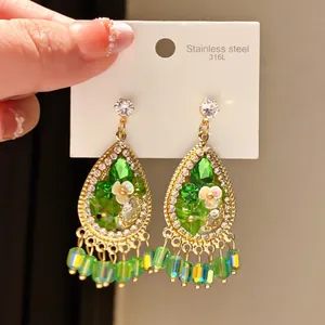 Macro detail of vintage teardrop earrings with green crystals and flower accents