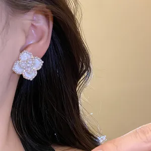 Primer plano de un elegante pendiente de perla con forma de flor usado en la oreja