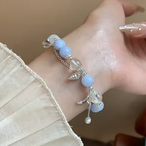 Détail exquis d'un élégant bracelet à breloques papillon en aigue-marine au poignet