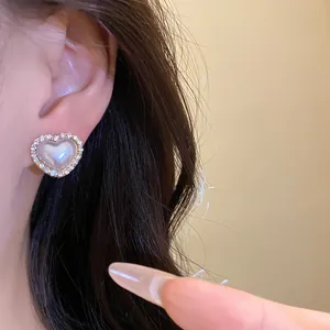 Primer plano de pendiente de perla en forma de corazón con borde de diamantes