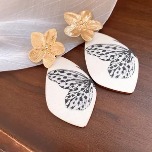 Elegant close-up of golden flower earrings with butterfly wing printed acetate pendants
