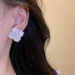 Primer plano detallado de un elegante pendiente de flor blanca con textura de perla