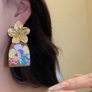 Detailed view of ethnic vintage earrings featuring a metal flower and floral acetate pendant
