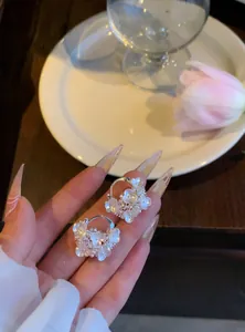 Vue détaillée de boucles d'oreilles créoles fleurs blanches et perles style français.