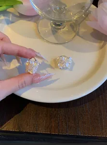 Détail de boucles d'oreilles florales de style français avec perles blanches et cristaux.