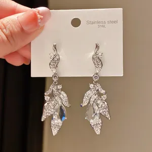 Detailed view of silver-toned drop earrings with zircon leaf and teardrop design