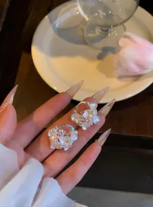 Gros plan de créoles de style français avec fleurs et perles tenues par une main