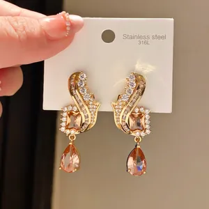 Close-up detail of vintage gold teardrop earrings with sparkling crystals on white display card