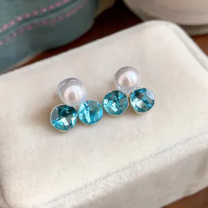 Detailed view of light luxury pearl and sky blue crystal earrings on velvet box
