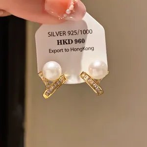 Close-up of elegant 925 silver pearl earrings featuring sparkling baguette-cut zircon stones