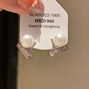 Exquisite detail of silver pearl stud earrings featuring sparkling baguette zircon accents