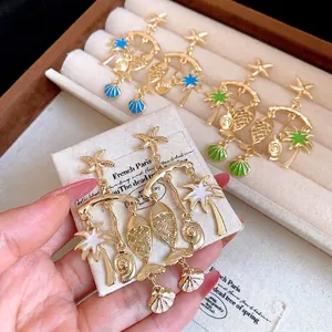 Gold-plated enamel beach earrings featuring starfish, fish, and palm tree charms.