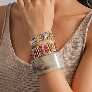 Close-up of vintage stacked bracelets with engraved letters and marble resin bangle