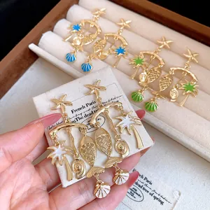 Detail view of gold-plated vacation earrings with starfish, palm tree, and fish charms.