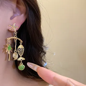 Close-up of gold ocean-themed dangle earrings featuring starfish and palm tree charms