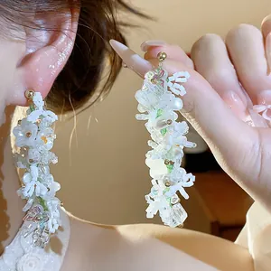 Eleganti orecchini in argento con fiori in vetro bianco, perle e dettagli a farfalla.