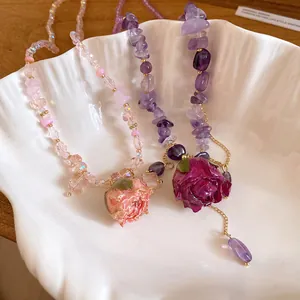 Detailed view of handmade amethyst and pink crystal necklaces with resin rose pendants.