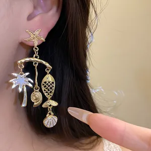Detail of gold nautical drop earrings with starfish, palm tree, and shell charms