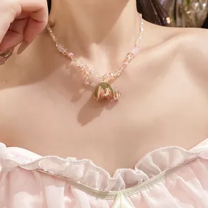 Detailed close-up of a romantic rose bud pendant on a delicate pink beaded clavicle necklace