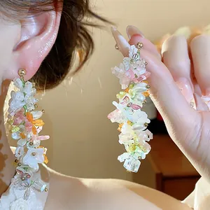 Dettaglio di orecchini a pendente con fiori e farfalle colorate in perline di vetro