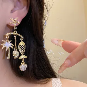 Close-up of gold ocean-themed drop earrings with starfish, palm tree, and shell details.