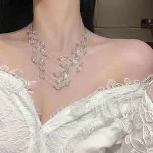Close-up detail of multi-layer crystal beaded necklace on an elegant white lace dress.